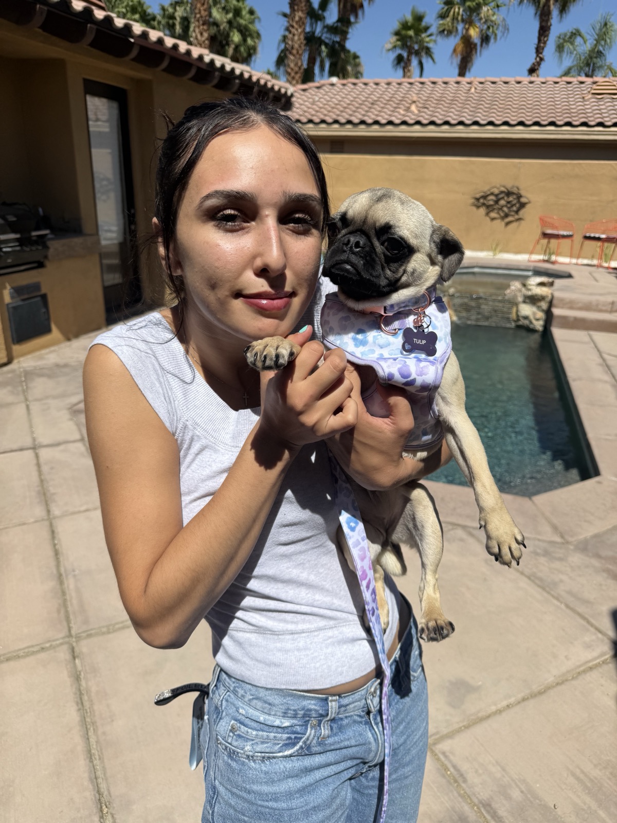 A Legacy Healing Foundation volunteer holding Tulip, a rescued pug, by the pool